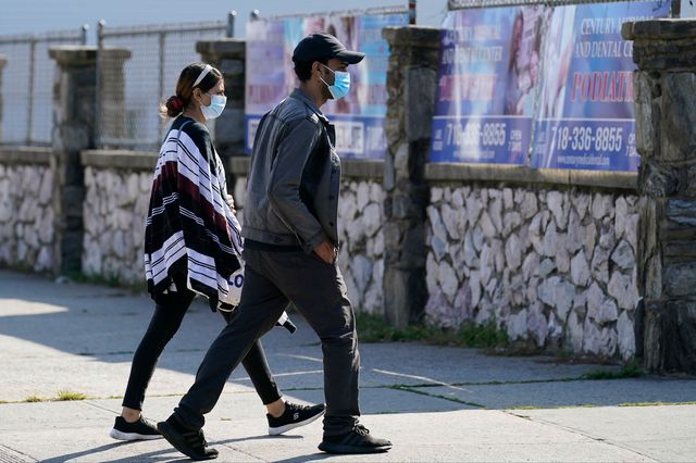 Two people wear protective face masks as they walk along a commercial street in Gravesend, Brooklyn on September 28th, 2020.